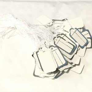 May include: A pile of white paper gift tags with blue trim and string attached. The tags are blank and ready to be written on.