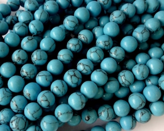 May include: A strand of turquoise blue beads with black veining. The beads are round and smooth, and they are strung together on a clear thread.