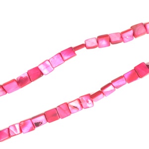May include: A strand of pink square-shaped beads made from mother of pearl. The beads are strung on a clear thread.
