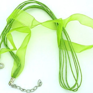 May include: A vibrant lime green necklace featuring multiple strands and a sheer ribbon detail. The necklace is secured with a silver-toned clasp and an adjustable chain. The design incorporates a variety of textures and a bright, summery colour.
