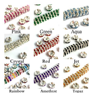 Peut inclure: Une collection de perles de strass et de garnitures perlées colorées, comprenant rose, vert, aqua, cristal, rouge, noir, arc-en-ciel, améthyste et topaze. Chaque couleur est étiquetée avec son nom.