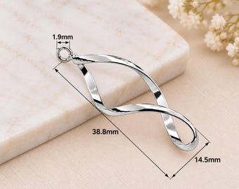 Könnte beinhalten: Ein silberfarbener Metallanhänger mit einem gedrehten, länglichen Design in Form einer offenen Schlaufe. Der Anhänger verfügt über einen kleinen runden Verbindungsring an der Oberseite. Technische Angaben zeigen eine Länge von 38,8 mm, eine Breite von 14,5 mm und einen Ringdurchmesser von 1,9 mm.