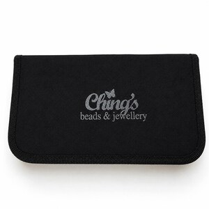 May include: A rectangular black fabric storage case with rounded corners and a thick stitched border. The center features the silver embroidered text Ching's beads & jewellery with a small butterfly icon above the letter i.