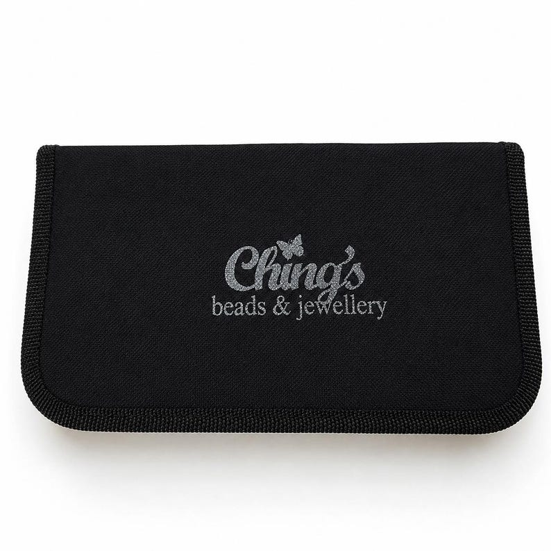 May include: A rectangular black fabric storage case with rounded corners and a thick stitched border. The center features the silver embroidered text Ching's beads & jewellery with a small butterfly icon above the letter i.