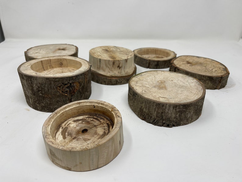 May include: A set of six wooden coasters made from tree bark. The coasters are round and have a natural, rustic look. They are perfect for adding a touch of nature to your home decor.