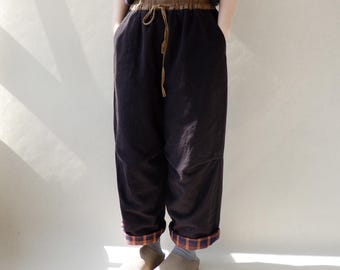 May include: Brown corduroy pants with a brown drawstring waist and plaid fabric trim at the cuffs.
