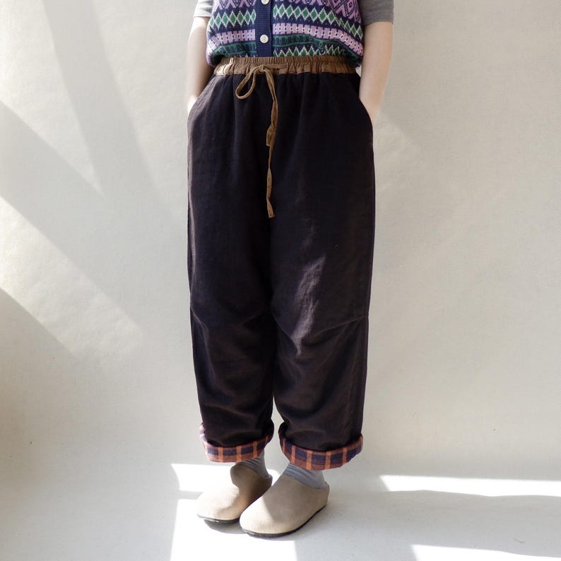 May include: Brown corduroy pants with a brown drawstring waist and plaid fabric trim at the cuffs.