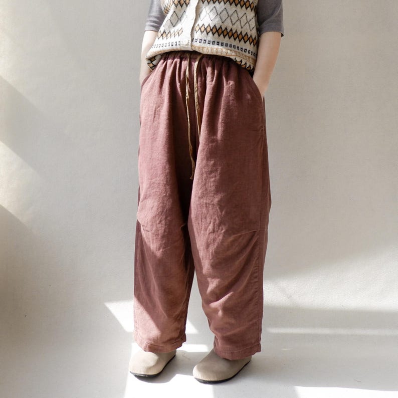 May include: A pair of loose-fitting, wide-leg pants in a deep burgundy color. The pants have a drawstring waistband and are made of a soft, textured fabric.