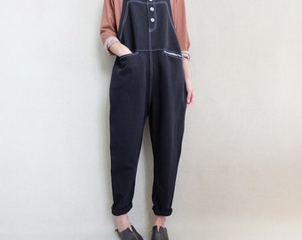 May include: Black overalls with white stitching and button closure. The overalls have a relaxed fit and are made of a soft, comfortable fabric.