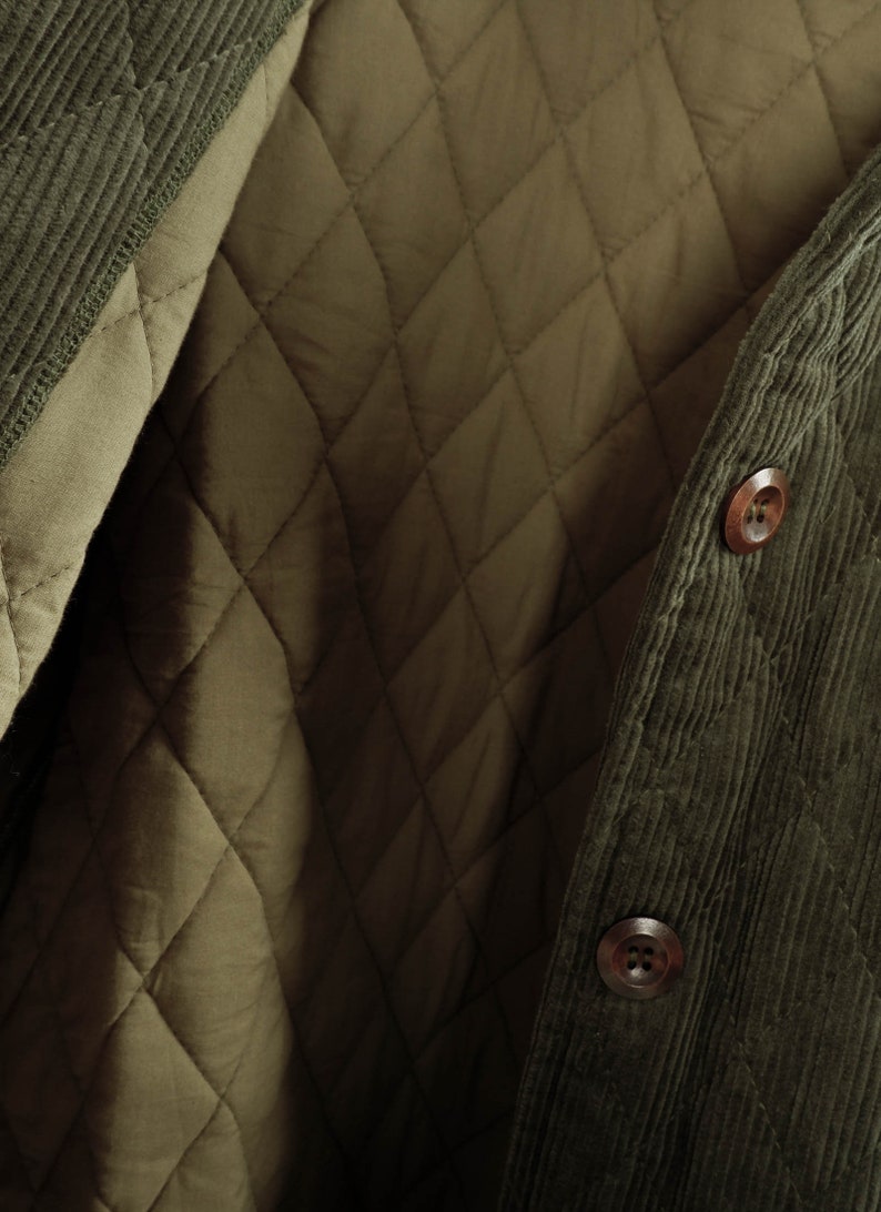 May include: A green corduroy jacket with a quilted lining. The jacket has a button closure and a corduroy collar.