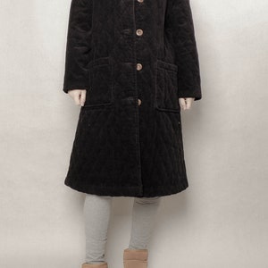 May include: A long black quilted corduroy coat with a button closure and two patch pockets.