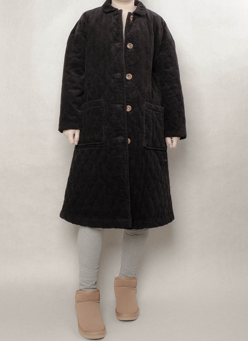 May include: A long black quilted corduroy coat with a button closure and two patch pockets.