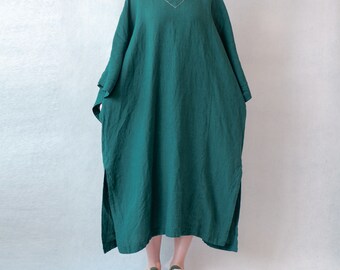 Puede incluir: Un vestido largo de lino verde esmeralda holgado con cuello en V y una abertura lateral. El vestido tiene un estilo sencillo y casual.