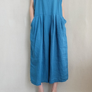 May include: A teal blue linen overall jumpsuit with wide legs and a square neckline. The straps are adjustable and the pockets are large.