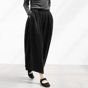 以下が含まれることがあります： ゆったりとしたシルエットの黒いワイドレッグパンツ。ハイウエストでリラックスして快適なスタイルです。