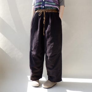 May include: Black wide-leg pants with a brown drawstring waist.