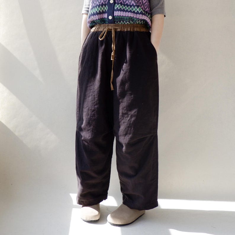 May include: Black wide-leg pants with a brown drawstring waist.