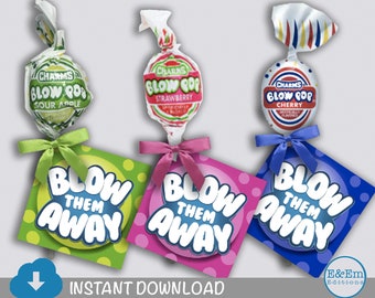May include: Three printable tags with the text "Blow Them Away" in a bubble font. Each tag is a different colour: green, pink, and blue. The tags are attached to lollipops with a ribbon. The lollipops are wrapped in white paper with the brand name "Charms" and the flavour "Blow Pop" printed on them. The flavours are Sour Apple, Strawberry, and Cherry.
