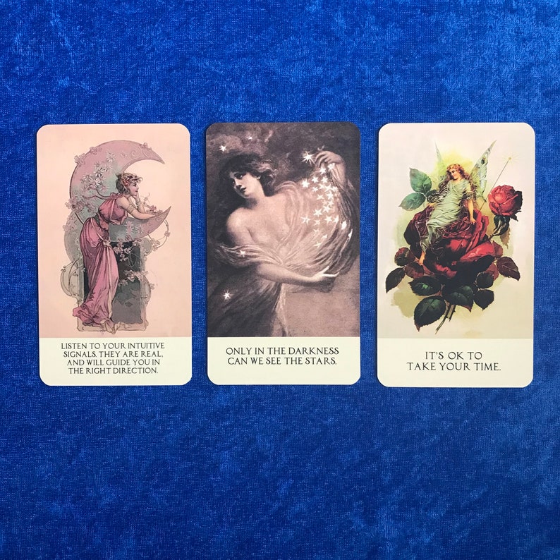 K&ouml;nnte beinhalten: Drei Tarotkarten mit Illustrationen und Text. Die erste Karte zeigt eine Frau, die unter einem Halbmond steht, mit dem Text "H&ouml;re auf deine intuitiven Signale, sie sind real. Und sie werden dich in die richtige Richtung f&uuml;hren.". Die zweite Karte zeigt eine Frau, die eine Handvoll Sterne h&auml;lt, mit dem Text "Nur in der Dunkelheit k&ouml;nnen wir die Sterne sehen". Die dritte Karte zeigt eine Fee, die auf einer roten Rose sitzt, mit dem Text "Es ist in Ordnung, sich Zeit zu nehmen."