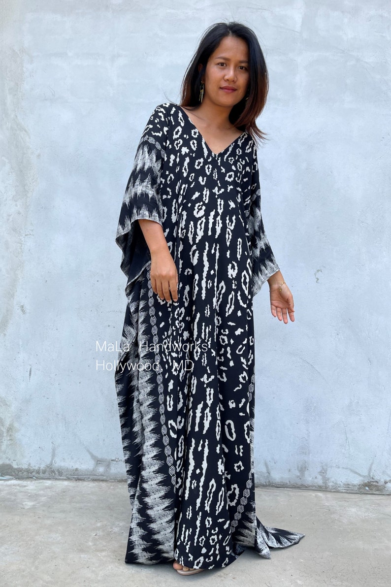 May include: A black and white maxi dress with a leopard print pattern. The dress has a V-neckline and long, flowing sleeves. The dress is made of a soft, comfortable fabric and is perfect for a casual or dressy occasion.