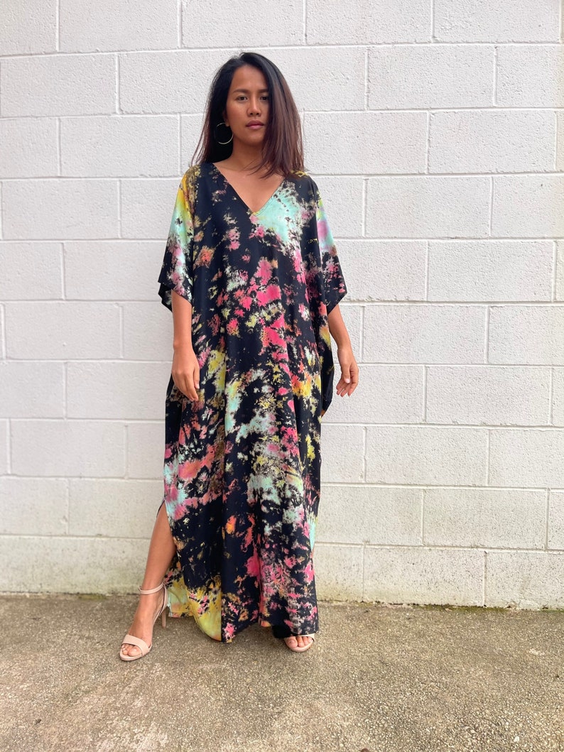 May include: A long black maxi dress with a tie-dye pattern in shades of pink, blue, and yellow. The dress has a V-neckline and short sleeves.