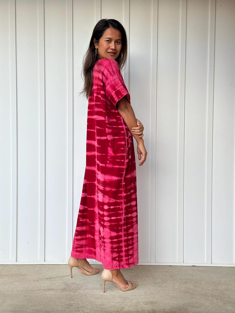 May include: A long, pink and white tie-dye maxi dress with short sleeves. The dress is made of a soft, flowing fabric and has a relaxed fit.