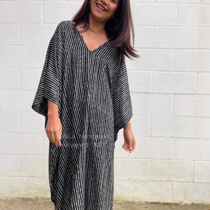 K&ouml;nnte beinhalten: Ein schwarz-wei&szlig; gestreiftes Kaftan mit V-Ausschnitt. Der Kaftan ist aus einem leichten Stoff gefertigt und hat eine lockere Passform.