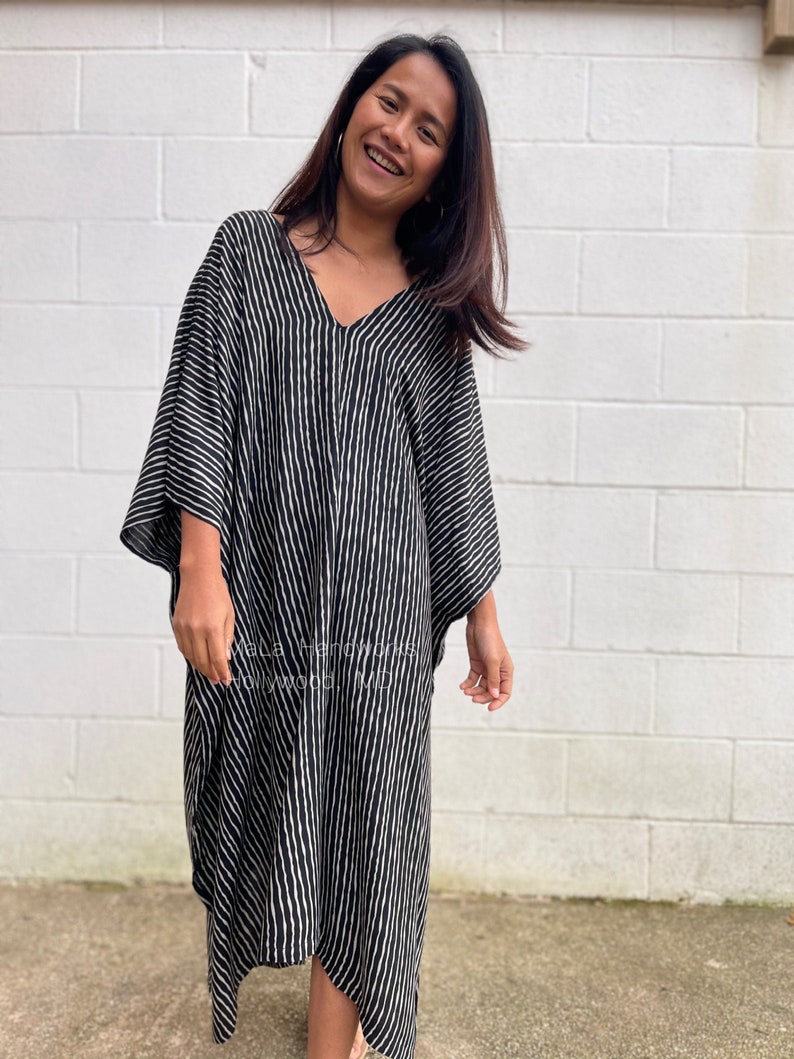 K&ouml;nnte beinhalten: Ein schwarz-wei&szlig; gestreiftes Kaftan mit V-Ausschnitt. Der Kaftan ist aus einem leichten Stoff gefertigt und hat eine lockere Passform.
