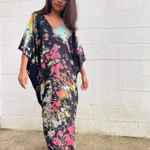 May include: A long black maxi dress with a tie-dye pattern in shades of pink, green, and yellow. The dress has a V-neck and short sleeves.