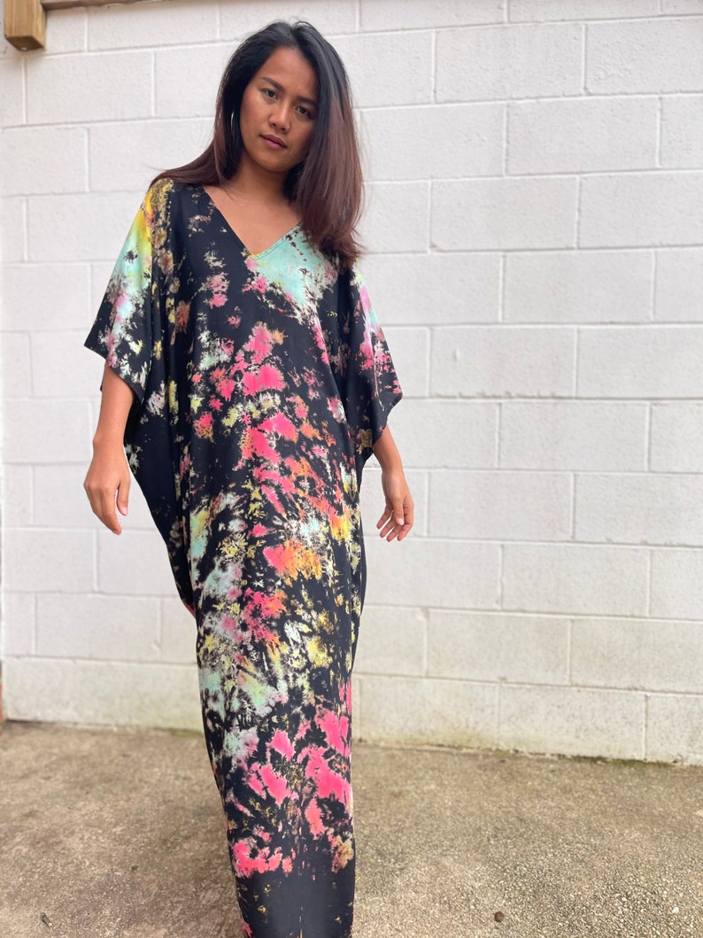 May include: A long black maxi dress with a tie-dye pattern in shades of pink, green, and yellow. The dress has a V-neck and short sleeves.