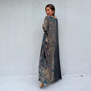 Może przedstawiać: Długa, zwiewna sukienka z wzorem tie-dye w odcieniach zieleni, brązu i czerni. Sukienka ma luźny, wygodny kr&oacute;j i okrągły dekolt.