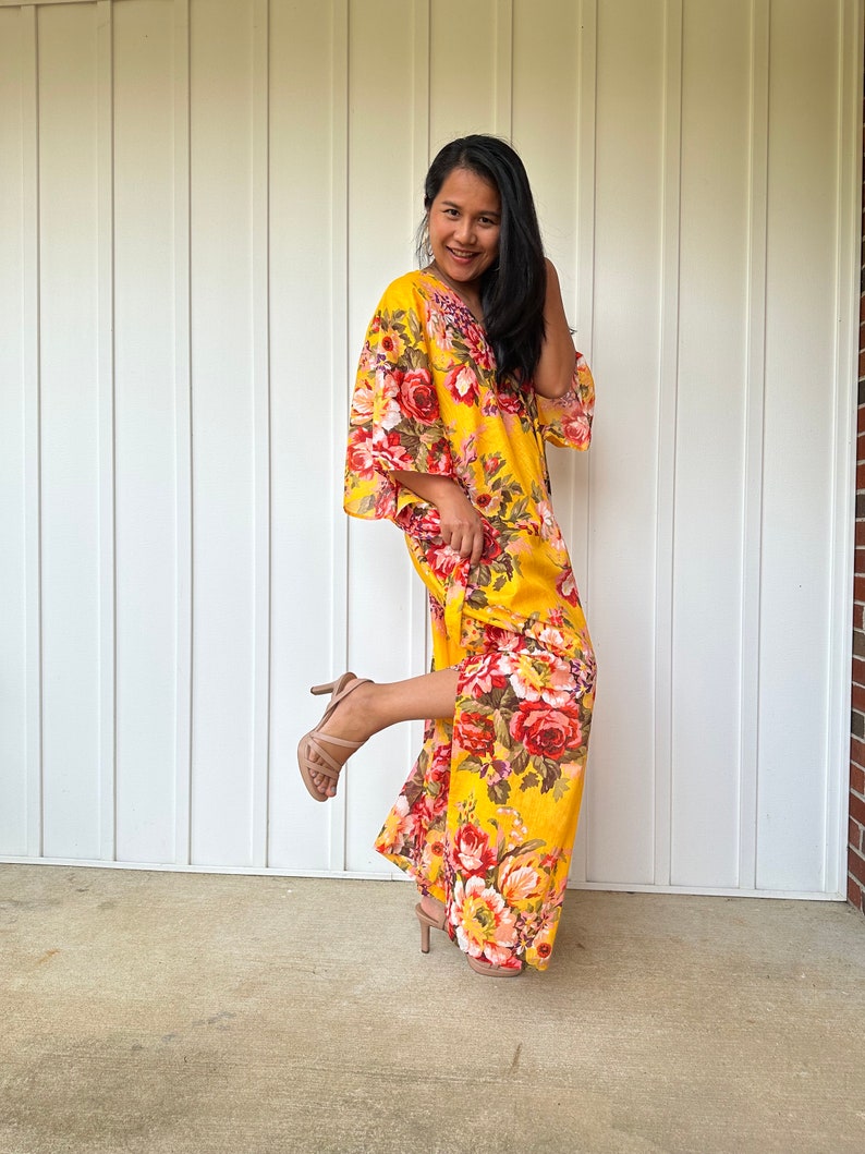 May include: A woman wearing a yellow maxi dress with a floral print. The dress has a V-neckline and 3/4 sleeves. She is wearing nude heels.