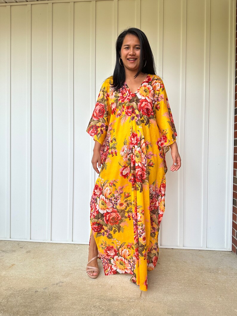 May include: A yellow maxi dress with a floral print. The dress has a V-neckline and 3/4 sleeves. The dress is flowy and has a relaxed fit.