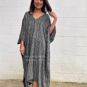 K&ouml;nnte beinhalten: Ein schwarz-wei&szlig; gestreiftes Maxikleid mit V-Ausschnitt und 3/4-&Auml;rmeln. Das Kleid ist aus einem leichten Stoff gefertigt und hat eine lockere Passform.