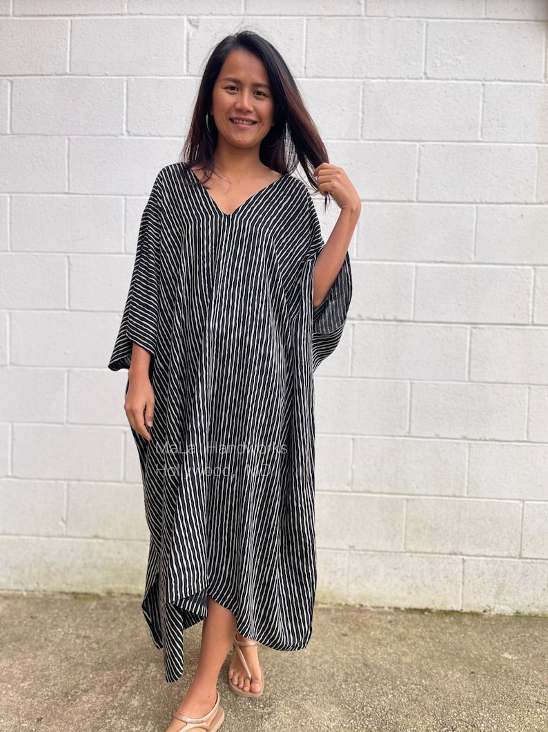 K&ouml;nnte beinhalten: Ein schwarz-wei&szlig; gestreiftes Maxikleid mit V-Ausschnitt und 3/4-&Auml;rmeln. Das Kleid ist aus einem leichten Stoff gefertigt und hat eine lockere Passform.