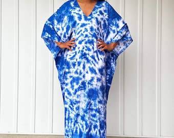May include: A long, blue and white tie-dye kaftan dress with a V-neckline. The dress has a relaxed fit and is made of a lightweight fabric.