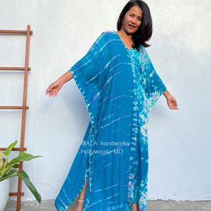 May include: A long, flowing blue and purple tie-dye maxi dress with a V-neck and side slits. The dress is made of a soft, comfortable fabric and has a relaxed fit. The dress is perfect for a casual day out or a night out on the town. MALA handworks Hollywood, MD.