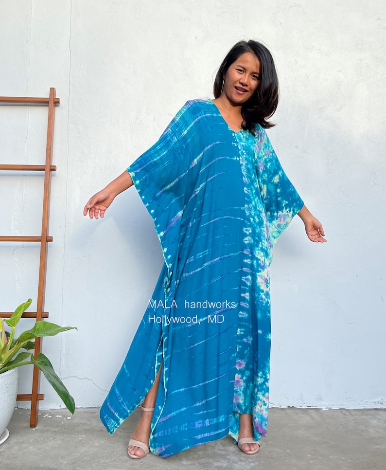 May include: A long, flowing blue and purple tie-dye maxi dress with a V-neck and side slits. The dress is made of a soft, comfortable fabric and has a relaxed fit. The dress is perfect for a casual day out or a night out on the town. MALA handworks Hollywood, MD.