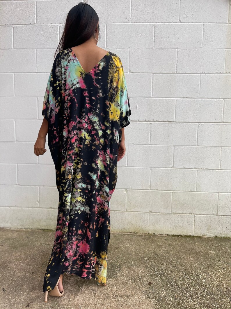 May include: A long, black maxi dress with a tie-dye pattern in shades of pink, yellow, and blue. The dress has a V-neck and short sleeves.