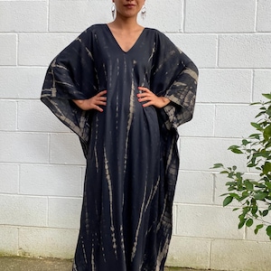 May include: A black and white tie-dye maxi dress with a V-neckline and long sleeves.