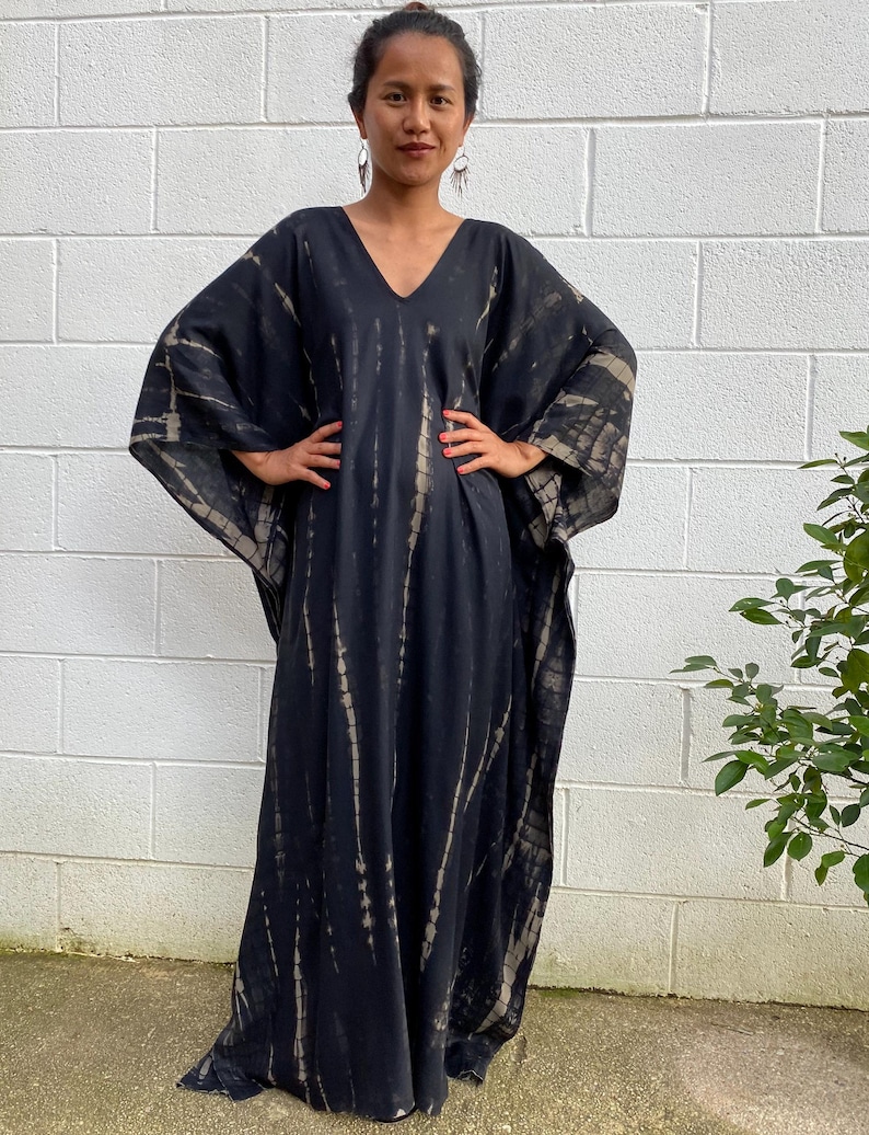 May include: A black and white tie-dye maxi dress with a V-neckline and long sleeves.