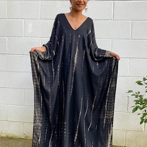 May include: A long, black and brown tie-dye maxi dress with a V-neckline and long sleeves.