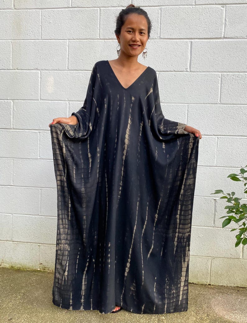 May include: A long, black and brown tie-dye maxi dress with a V-neckline and long sleeves.