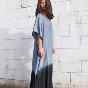 May include: A long, flowing gray and black ombre dress with a loose, comfortable fit. The dress has a simple, elegant design and is perfect for a variety of occasions.