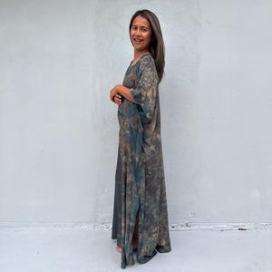 Może przedstawiać: Kobieta w długiej, zwiewnej, zielono-brązowej sukience maxi z tie-dye o luźnym, swobodnym kroju.
