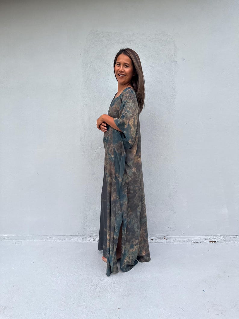 Może przedstawiać: Kobieta w długiej, zwiewnej, zielono-brązowej sukience maxi z tie-dye o luźnym, swobodnym kroju.