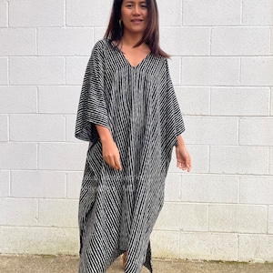 K&ouml;nnte beinhalten: Ein schwarz-wei&szlig; gestreiftes Kaftan mit V-Ausschnitt. Der Kaftan ist aus einem weichen, flie&szlig;enden Stoff gefertigt und hat eine lockere Passform.