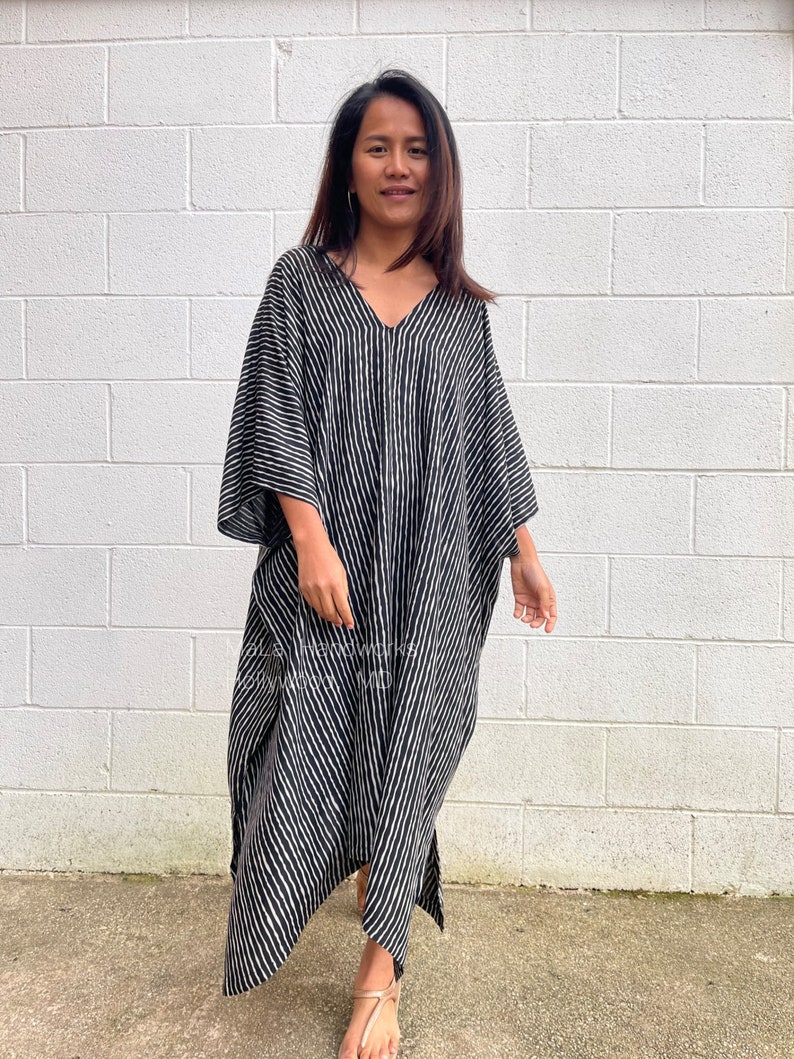 K&ouml;nnte beinhalten: Ein schwarz-wei&szlig; gestreiftes Kaftan mit V-Ausschnitt. Der Kaftan ist aus einem weichen, flie&szlig;enden Stoff gefertigt und hat eine lockere Passform.