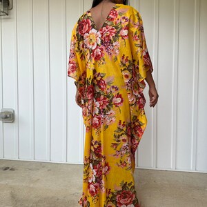 May include: A yellow maxi dress with a floral print. The dress has a V-neckline and a flowing silhouette.