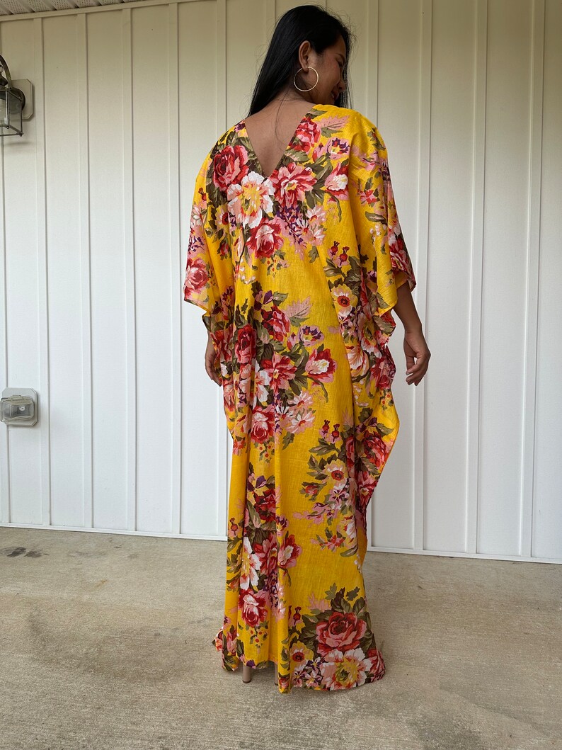 May include: A yellow maxi dress with a floral print. The dress has a V-neckline and a flowing silhouette.
